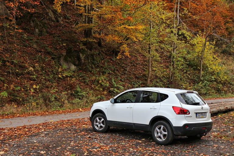 Nissan Qashqai crossover SUV compact car parked next to a hiking trail in Beskidy, Poland.