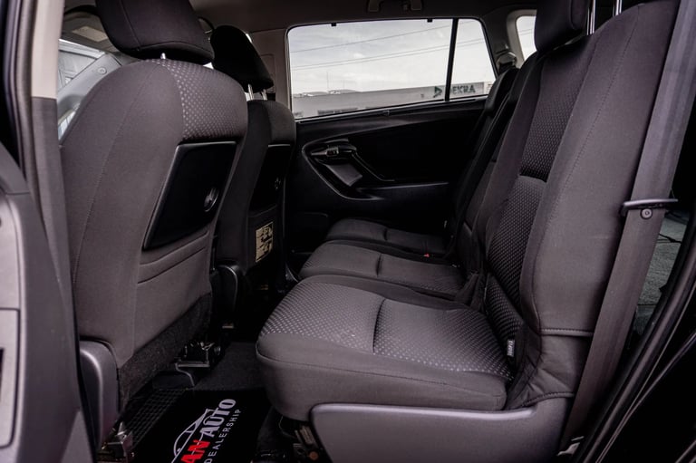 Interior rear seats of a vehicle with gray upholstery, showing spacious seating area with windows visible in background