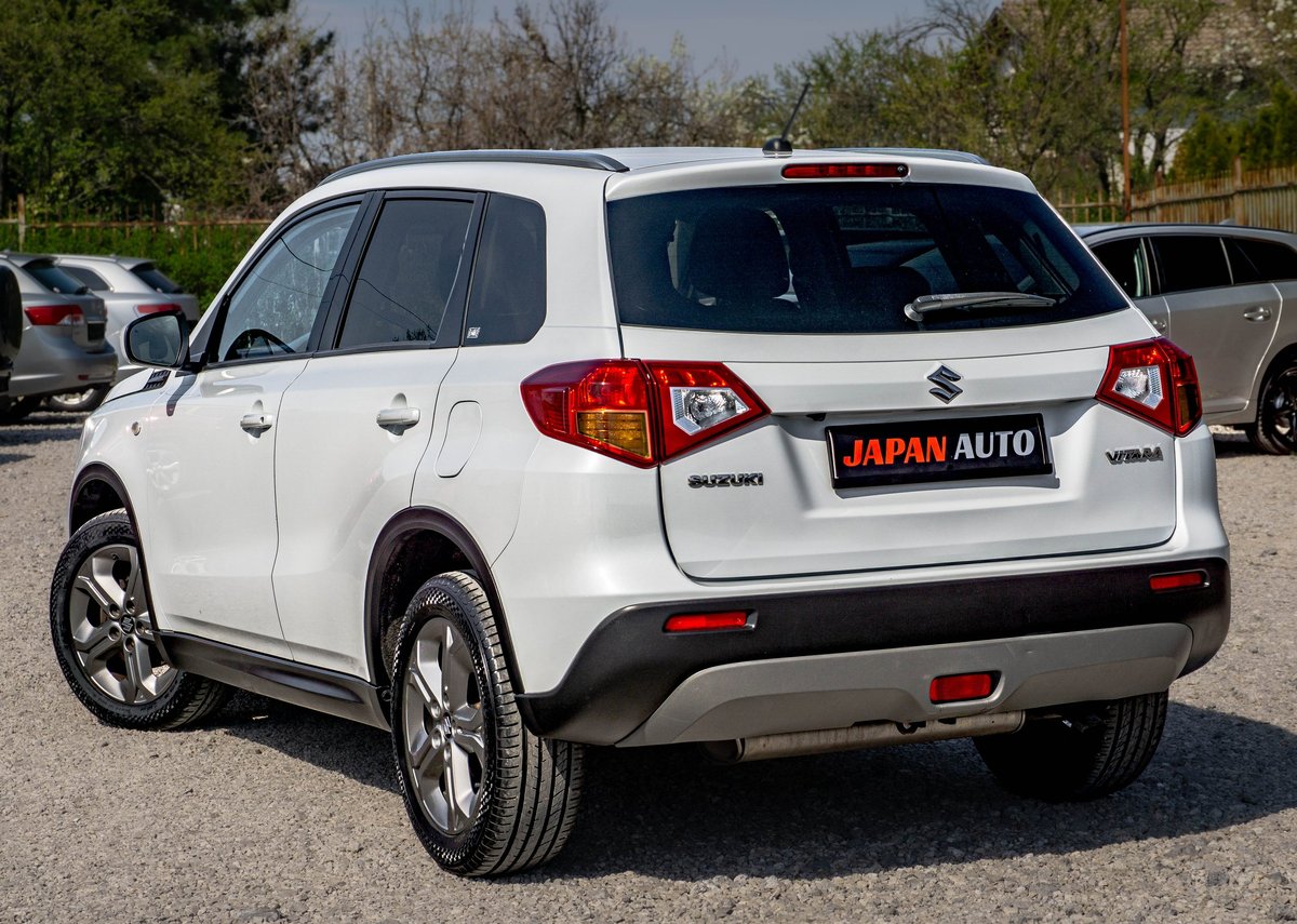 White Suzuki SUV with Japan Auto license plate, rear view in outdoor parking lot