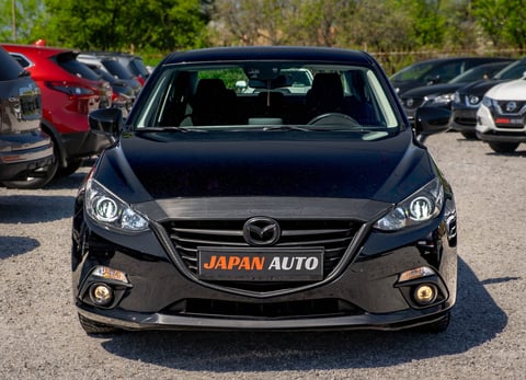 Black Mazda sedan at Japan Auto dealership lot with red car visible in background