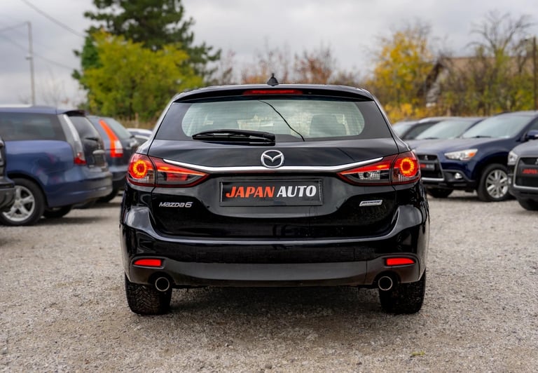 Black Mazda car rear view in parking lot with JAPAN AUTO license plate and other vehicles visible in background