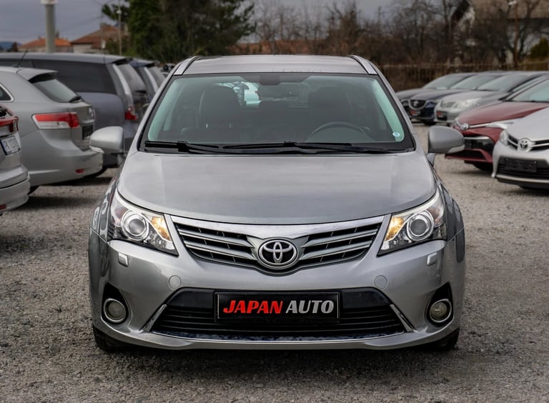 Silver Toyota minivan with Japan Auto license plate parked in a used car lot with other vehicles