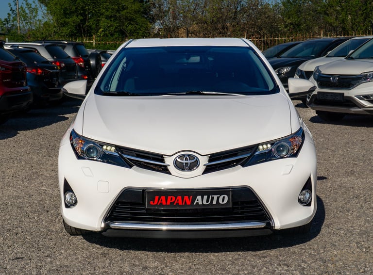 White Toyota Auris parked in car dealership lot with red Japan Auto badge on grille