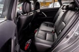 Interior view of a car showing black leather rear seats with red safety harness and headrests