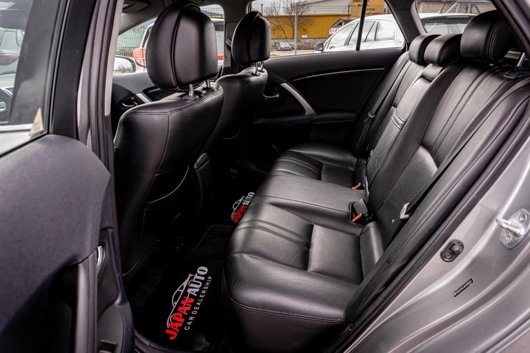 Interior view of a car showing black leather rear seats with red safety harness and headrests