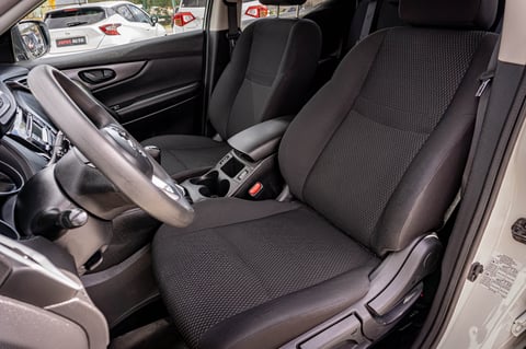 Interior view of a car showing black fabric seats, steering wheel, and dashboard through open driver-side door