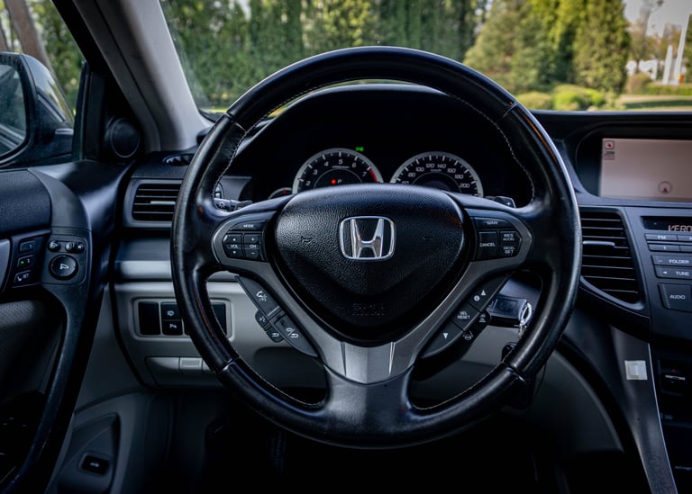 Honda steering wheel and dashboard interior view with speedometer and control buttons visible