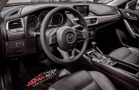 Modern car interior with black leather steering wheel, dashboard, digital display, and center console in a luxury vehicle