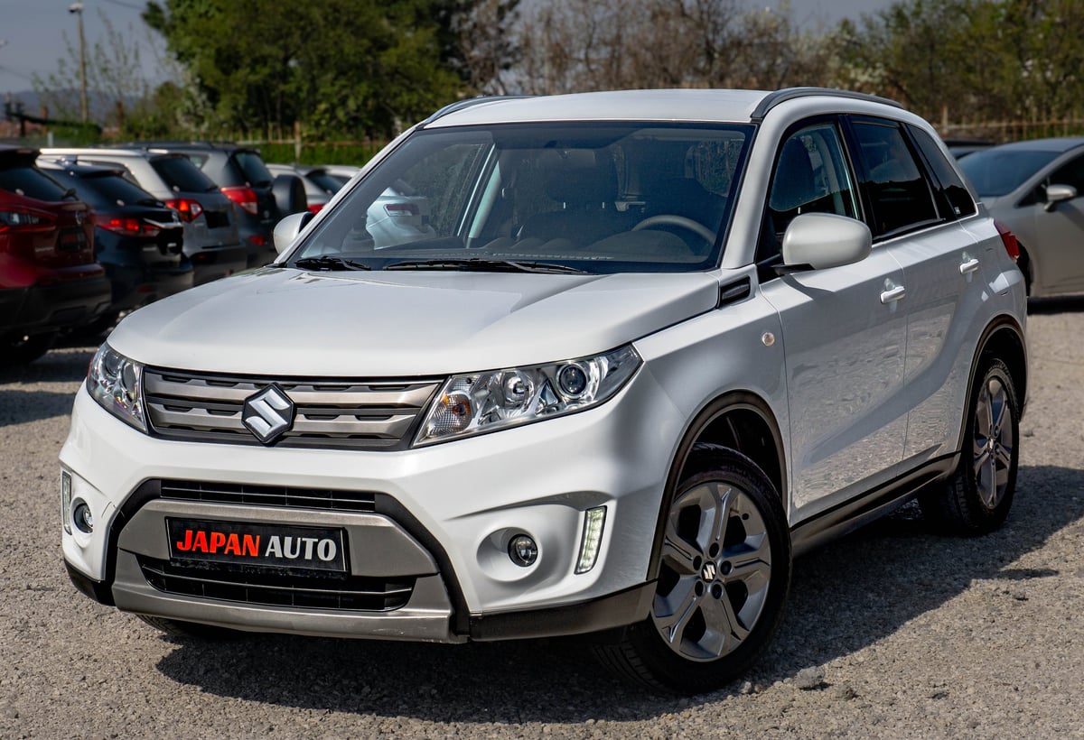White Suzuki Vitara SUV parked in a lot with Japan Auto dealership plate visible