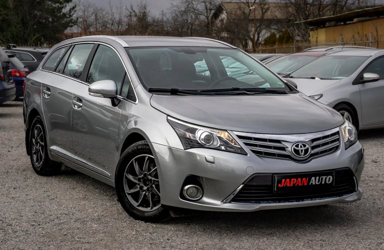Silver Toyota Avensis sedan parked at car dealership with other vehicles in background