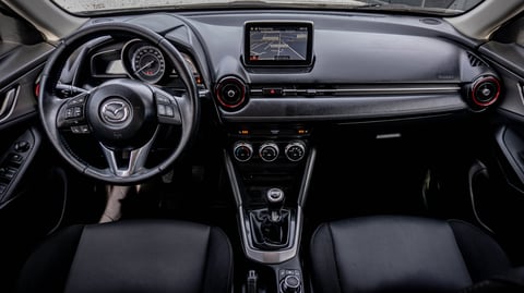 Modern car interior dashboard with steering wheel, touchscreen display, climate controls, and black leather seating