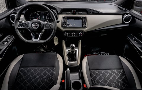 Modern car interior dashboard with steering wheel, touchscreen display, and black leather seats with quilted pattern