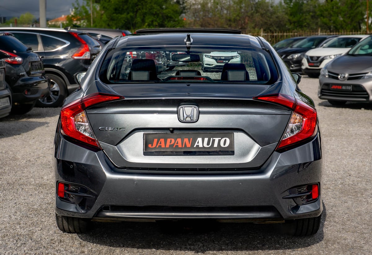 Gray Honda sedan parked at Japan Auto dealership lot with other vehicles visible in background