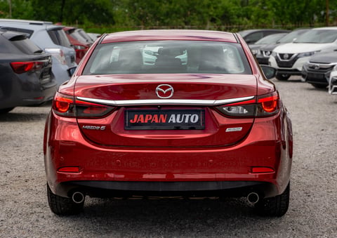 Red Mazda car rear view with Japan Auto dealer plate in parking lot