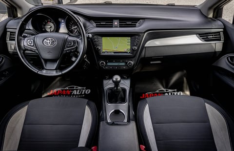 Interior of a Toyota vehicle showing steering wheel, dashboard with navigation screen, and front seats with gray and black upholstery