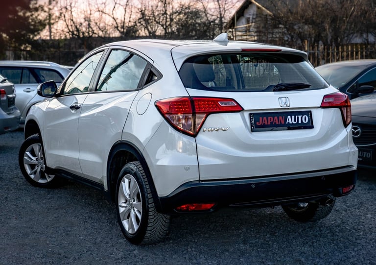 White Honda HR-V SUV parked at a dealership, shown from the rear three-quarter angle with trees in the background
