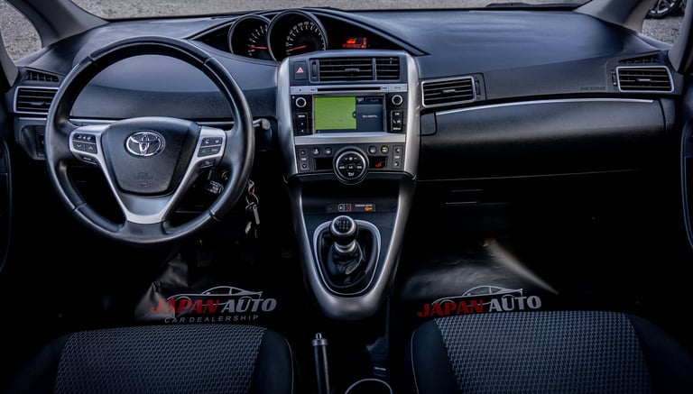 Interior dashboard view of a Toyota vehicle with steering wheel, touchscreen display, and dark interior panels