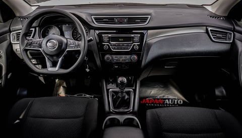 Interior view of a Nissan vehicle showing steering wheel, dashboard, center console, and front seats with dark upholstery