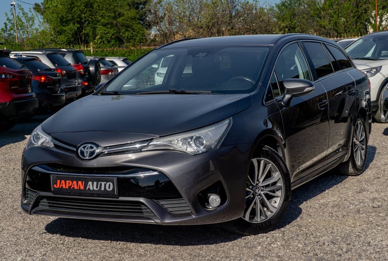 Black Toyota minivan parked at a car dealership lot with other vehicles in the background