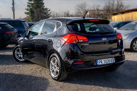 Black Kia compact hatchback parked in a lot, rear three-quarter view showing tailgate and alloy wheels