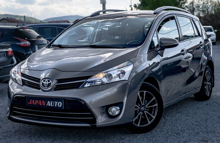 Silver Toyota minivan parked at a dealership lot with Japan Auto branding