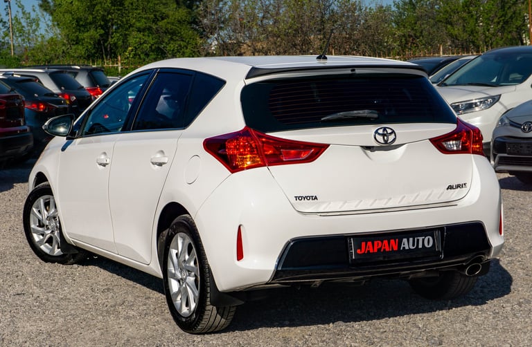 White Toyota Auris hatchback car viewed from the rear three-quarter angle in a parking lot