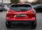 Red Nissan Qashqai SUV rear view with Japan Auto license plate in a parking lot