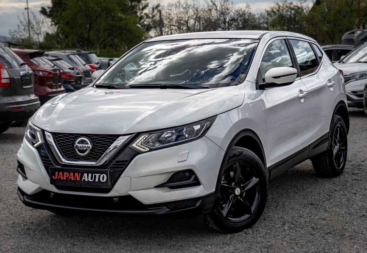 White Nissan Qashqai SUV parked in a car dealership lot with other vehicles visible in the background