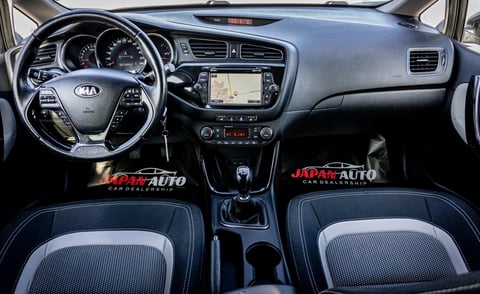 Interior of a Kia vehicle showing steering wheel, dashboard with infotainment system, and blue and black upholstered front seats