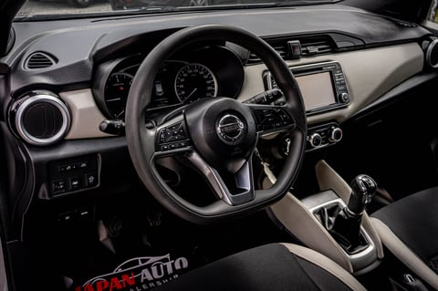 Modern car interior with black steering wheel, digital dashboard, and beige and black trim on a dark background
