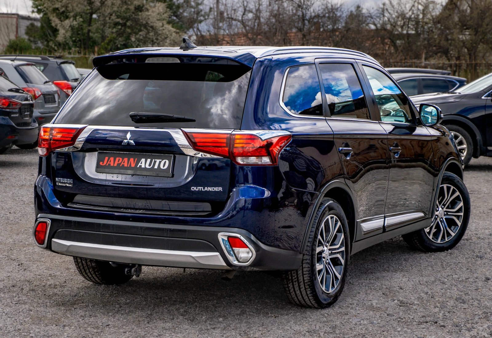 Black Mitsubishi Outlander SUV rear view in car dealership lot with other vehicles visible
