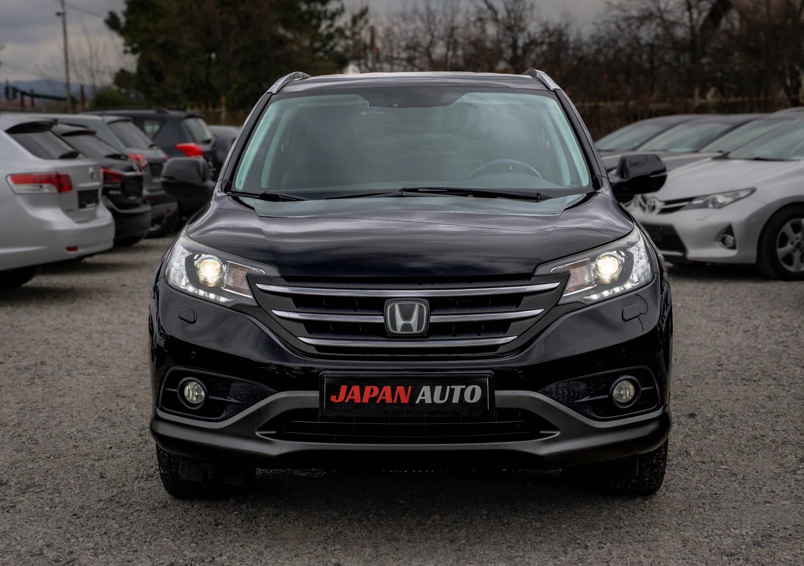 Black Honda CR-V SUV photographed head-on at a car dealership lot