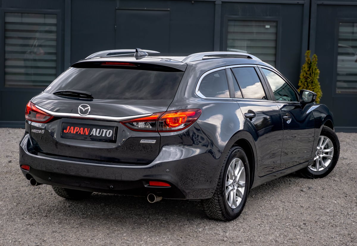 Black Mazda SUV parked in front of dark garage doors with Japan Auto license plate visible