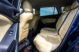 Interior view of blue car showing beige leather rear seats