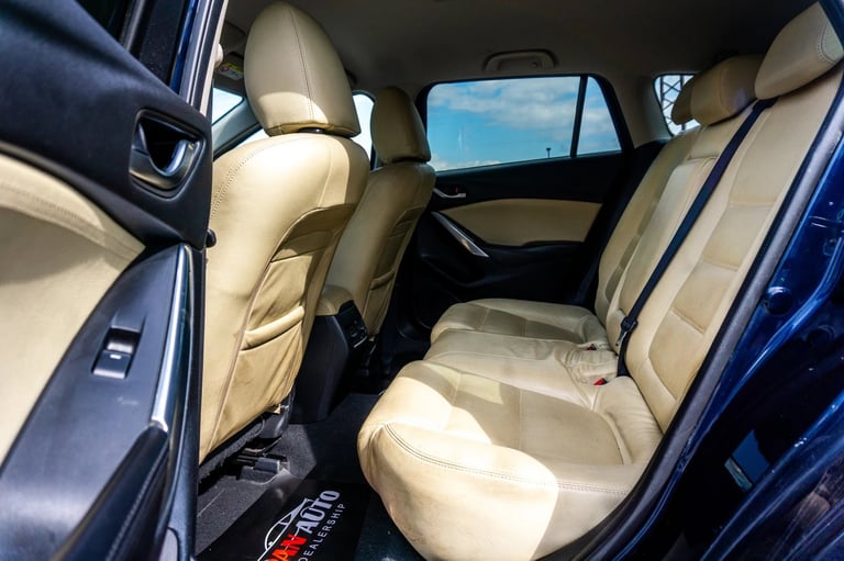 Interior view of a blue car showing beige leather rear seats with windows and door panels visible