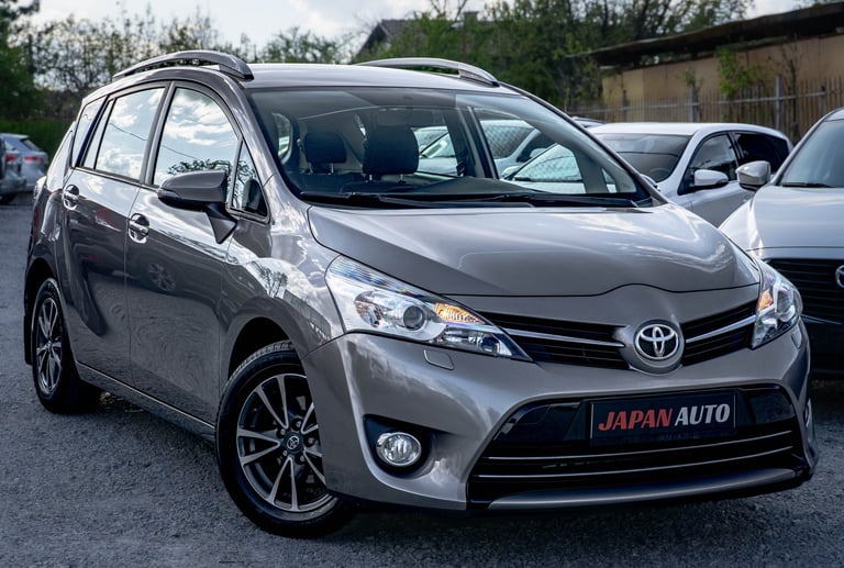 Silver Toyota minivan parked at a dealership with Japan Auto branding on the license plate