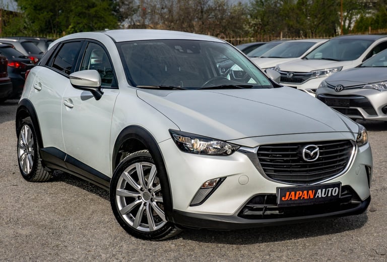 White Mazda CX-3 compact SUV parked in a lot with alloy wheels and JAPAN AUTO dealer plate visible