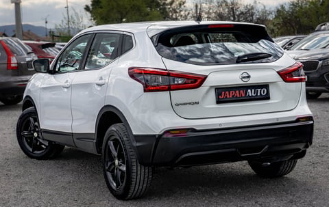 White Nissan Qashqai crossover SUV parked at a car dealership, rear three-quarter view