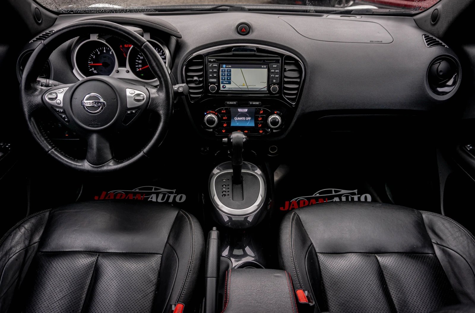 Black car interior with steering wheel, dashboard, infotainment system, and leather bucket seats