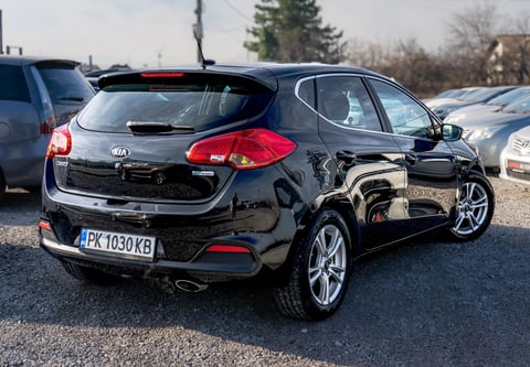 Black Hyundai i30 hatchback car parked in a lot, rear three-quarter view showing red taillights and alloy wheels