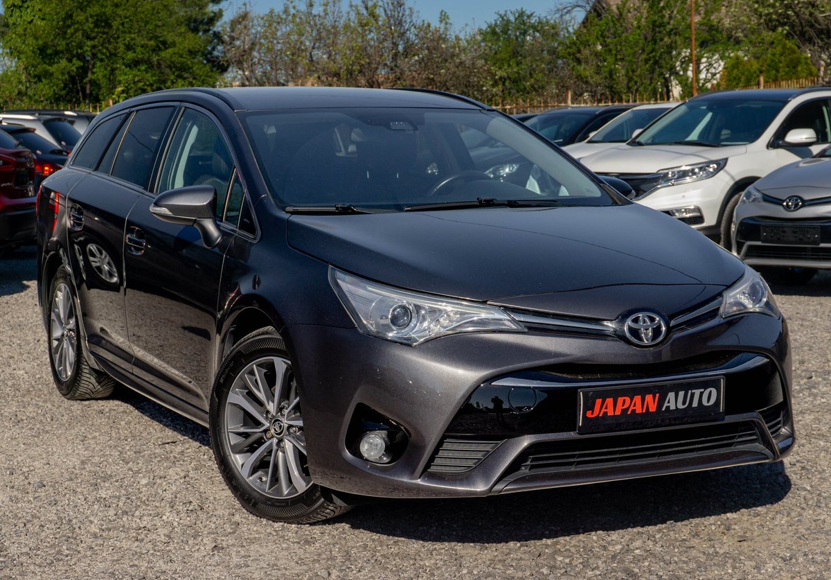 Dark gray Toyota Avensis sedan parked in a lot with other vehicles, featuring chrome accents and a Japan Auto dealer plate