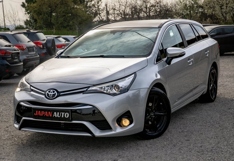 Silver Toyota Avensis station wagon parked in a lot with Japan Auto branding on the front bumper