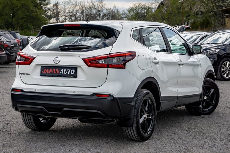 White Nissan Qashqai SUV displayed from the rear three-quarter view in a car lot with other vehicles visible in the background