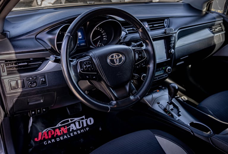 Interior of a Toyota vehicle showing the steering wheel, dashboard, and center console at an auto dealership