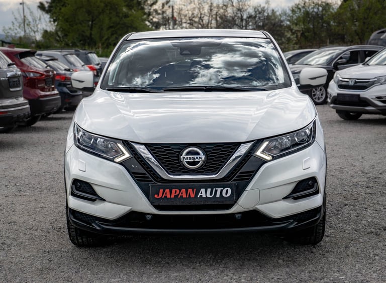 White Nissan Qashqai SUV parked at Japan Auto dealership lot with other vehicles in background