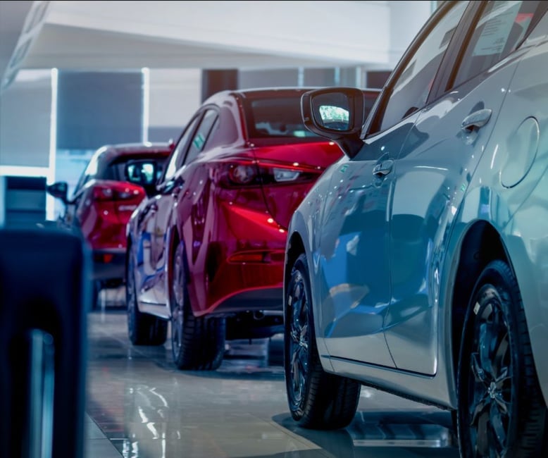 Row of new vehicles displayed in modern car showroom with bright white and blue lighting