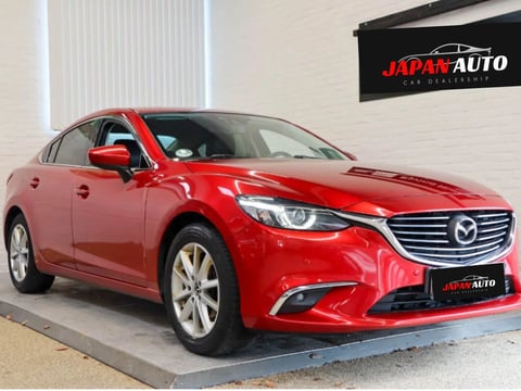 Red four-door sedan parked on pavement outside a building
