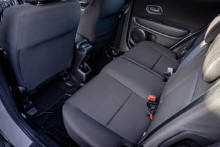 Interior view of a car showing back seat with dark gray upholstery and seat belt visible