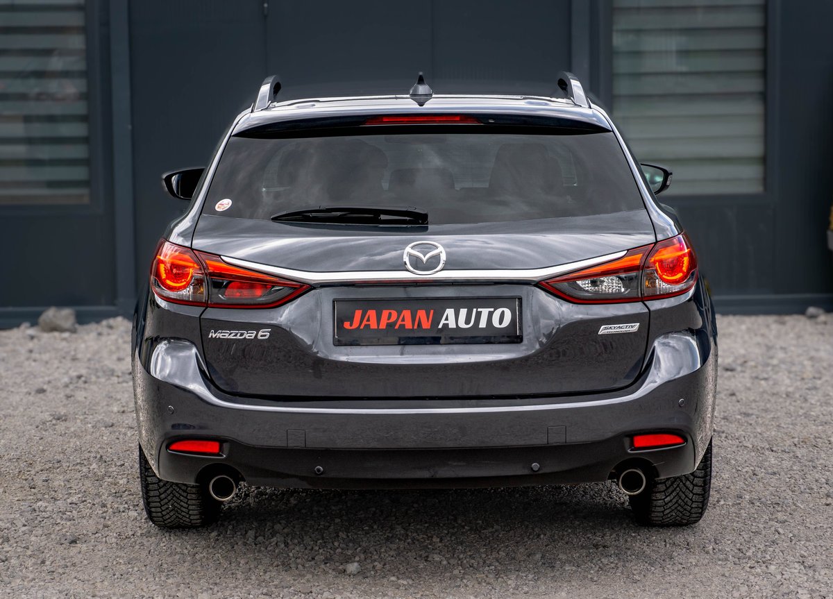 Rear view of black Mazda sedan with illuminated red taillights and Japan Auto license plate