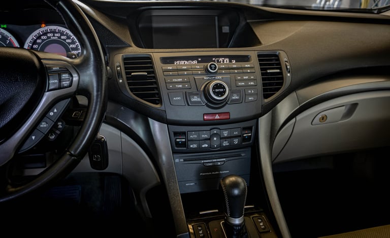 Interior view of a car dashboard showing steering wheel, center console with radio and climate controls, and tan colored seats